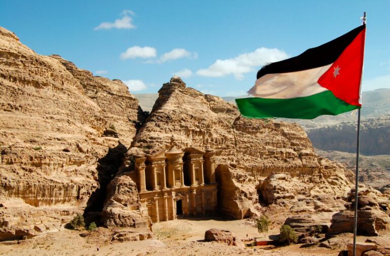 علم الأردن وفي المشهد مدينة البترا الأثرية